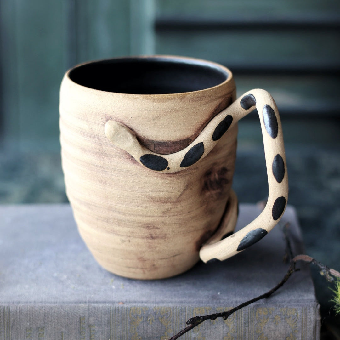 Ceramic mug with a unique handle design on a book
